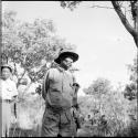 Bojo wearing Western clothing, standing, with an expedition member standing behind him