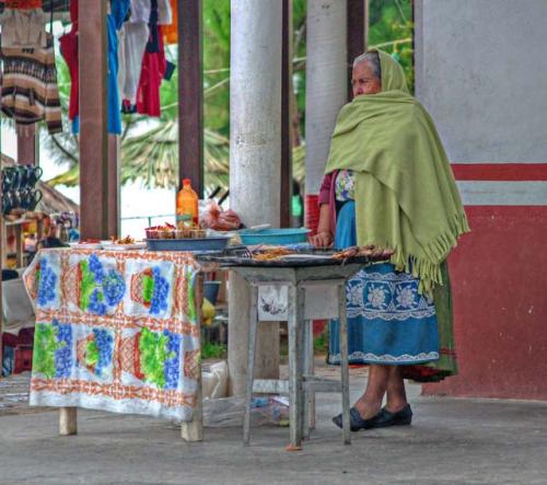 "Vendor: a woman selling fried pescado blanco awaits customers"
