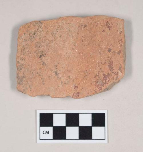 Coarse red bodied earthenware body sherd, with fragments of red and buff slip, reduced core