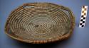 Small basket tray, coiled. 4 handles. Made of bear grass and devil's claw.
