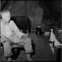 John Marshall sitting next to film equipment inside an expedition tent