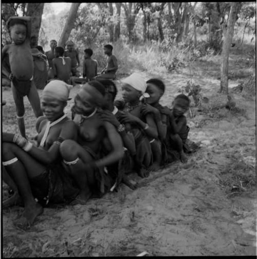 Group of women and girls playing N≠ahng !Au!uh (the snake game), sitting in a line