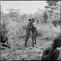 Two boys wrestling, with others sitting near them