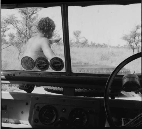 Man sitting on the front of the expedition Jeep, pointing, guiding the group to a hunting area