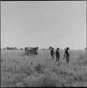 Three hunters walking, with the expedition jeep behind them