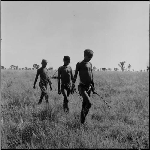 Three hunters walking, carrying bows and quivers