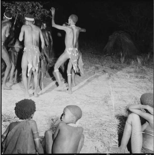 Group of men dancing, with a boy dancing in the center of them, in a night dance