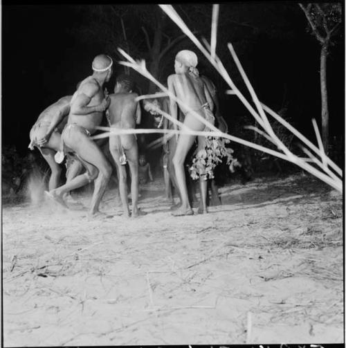 Five men and boys dance with their backs to the camera in a night dance