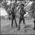 Boy preparing to chop at a tree stump with an axe, with another boy standing next to it