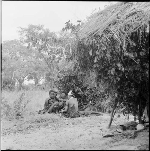 Group of women sitting and lying down next to a shelter skerm