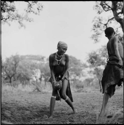 Woman passing a ball to another woman, playing tamah n!o’an (ball game) / !’hu kuitzi (veldkos game)