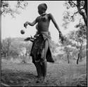 Girl tossing a ball to ≠Nisa, standing behind her, playing tamah n!o’an (ball game) / !’hu kuitzi (veldkos game)