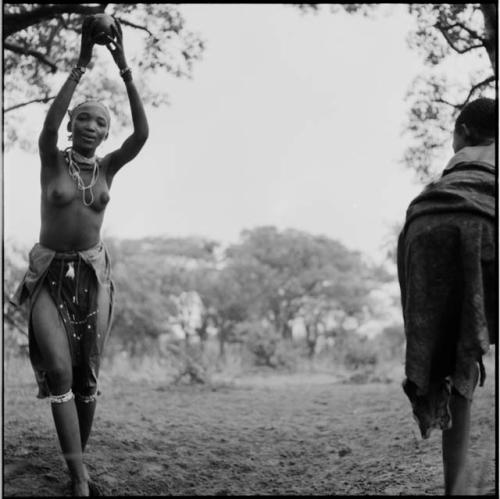 Woman catching a ball, playing tamah n!o’an (ball game) / !’hu kuitzi (veldkos game) with a group of women and girls