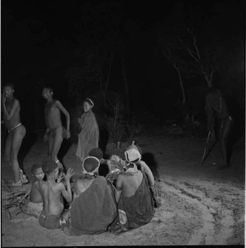 Boys dancing near a group of women sitting and clapping in a night dance