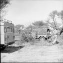 Man walking with John Marshall and another expedition member toward the expedition Jeep, view from behind