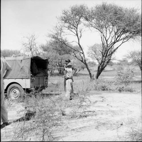 Man standing with two expedition members behind the Jeep, with another man sitting inside the Jeep