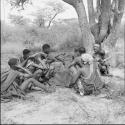 /Ti!kay curing a woman who is lying sick in a circle of women