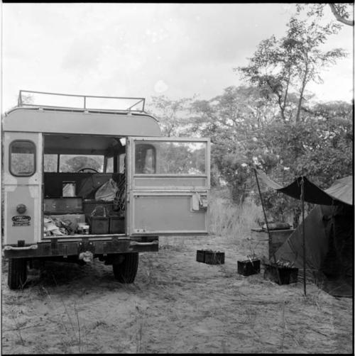 Luggage inside the expedition Land Rover, with a shelter next to it, equipment on the ground