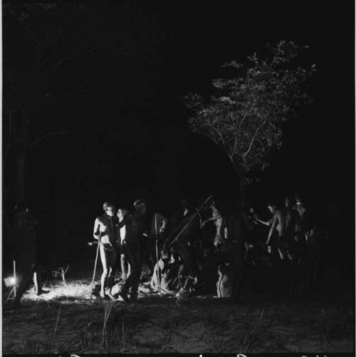 Men dancing around a group of women sitting, clapping and singing for a night dance