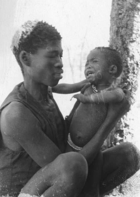 Chihumbo (daughter of Naka and N//ui) being held by an unnamed person