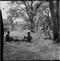 //Ao and !Naishi sitting, making a //guashi, with Robert Gardner photographing them