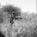 Hunter carrying a piece of meat to the expedition Jeep, with people sitting and standing in the grass in the background