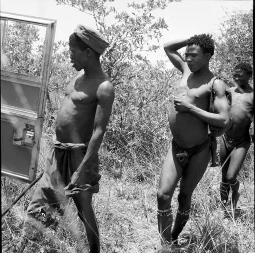 "Short /Qui" and two other hunters walking to the expedition Jeep in a line