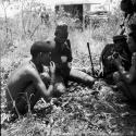 Five men eating meat from their hunt, with the expedition Jeep in the background