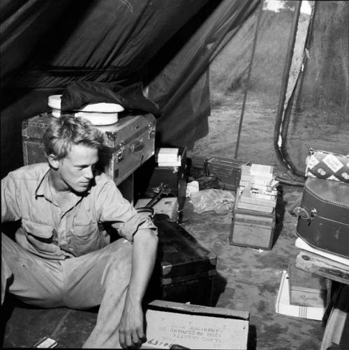 John Marshall sitting with film equipment inside an expedition tent