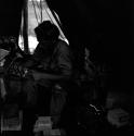 John Marshall looking at a box of film, sitting with film equipment inside an expedition tent