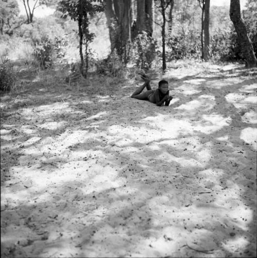 Boy lying on the sand, propping himself up on his elbows