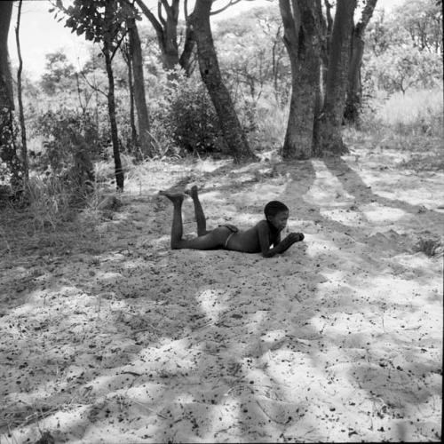 Boy lying on the sand, propping himself up on his elbows