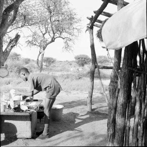 Man washing dishes on a table next to the expedition hut