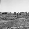 Group of people walking toward an expedition truck, going to a pan to wash clothes