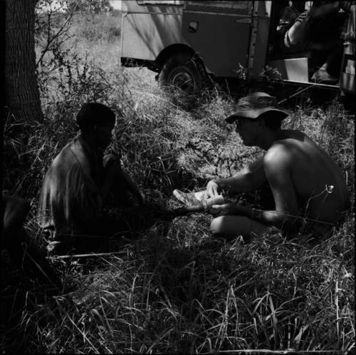 "Short /Qui" sitting with Nicholas England, who is holding the end of his leg