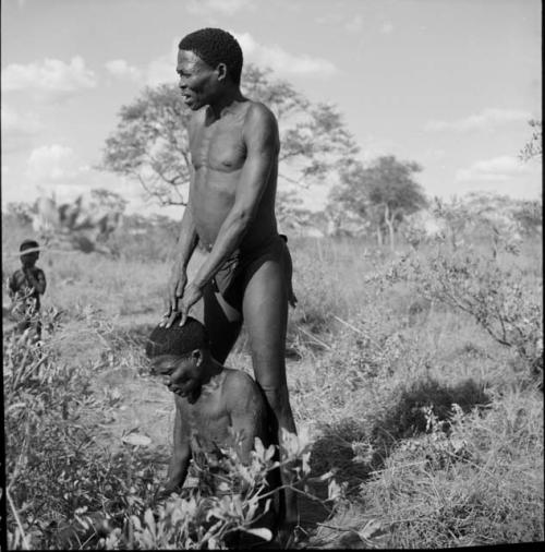 Man standing, caring for another man in trance at a daytime dance