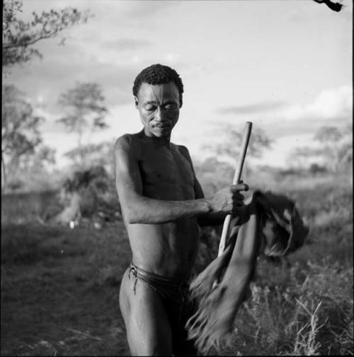 Man standing at a daytime dance, holding a stick and a cloth