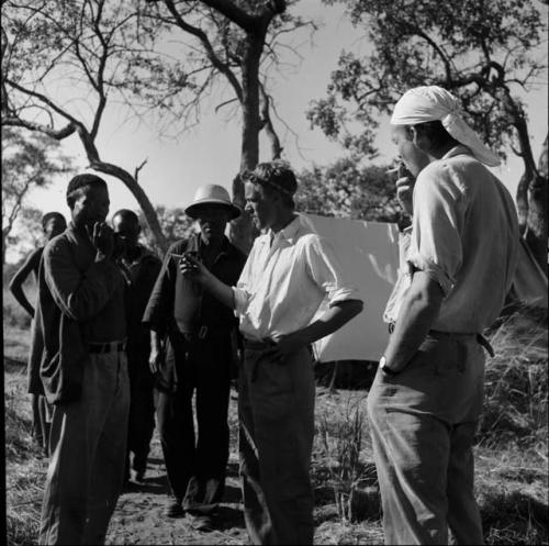 /Ti!kay standing with John Marshall and other expedition members, talking