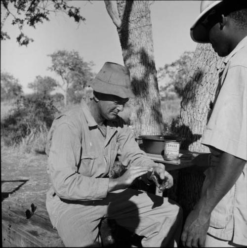 Expedition member standing next to Nicholas England who is wiping "Smeermiddels" on his hand