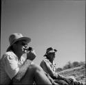 Robert Gardner sitting with another expedition member, smoking