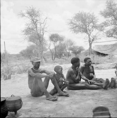 ≠Toma, two men and a boy siting in the expedition camp