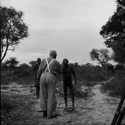 ≠Toma standing with Laurence Marshall, with /Ti!kay standing in the background