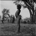 Boy standing, profile, with people sitting and standing in the background