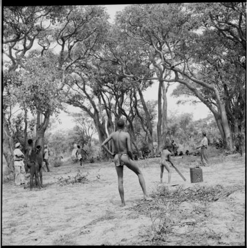 Men playing baseball with expedition members, with the pitcher running to catch the ball