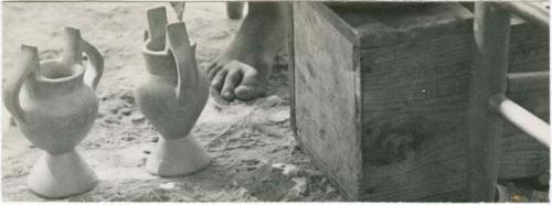 Two ceramic vessels on ground next to crate