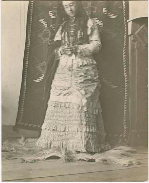 Adella Hubbrll in her grandmother's dress, in front of Navajo blanket