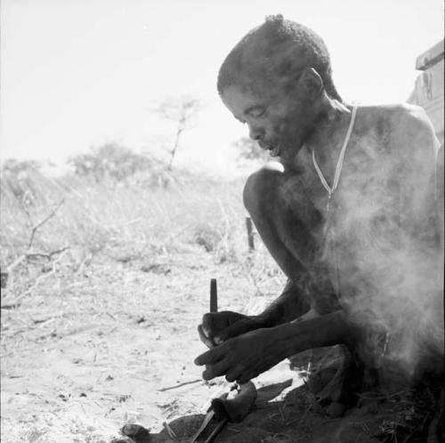 "/Gao Music" squatting next to a fire, working