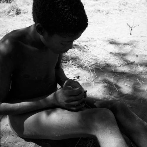 Man stringing cocoons to make dance rattles