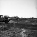 Two women walking with John Marshall near the expedition Land Rover