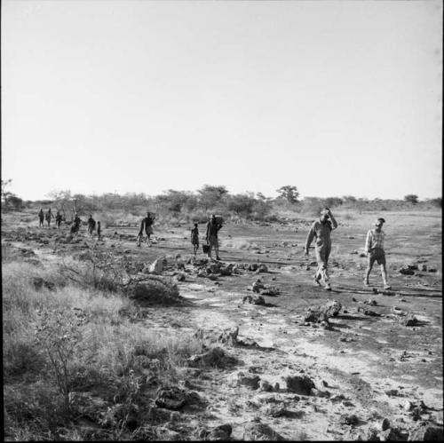 People walking in a line in the veld, with two expedition members in the front of the line